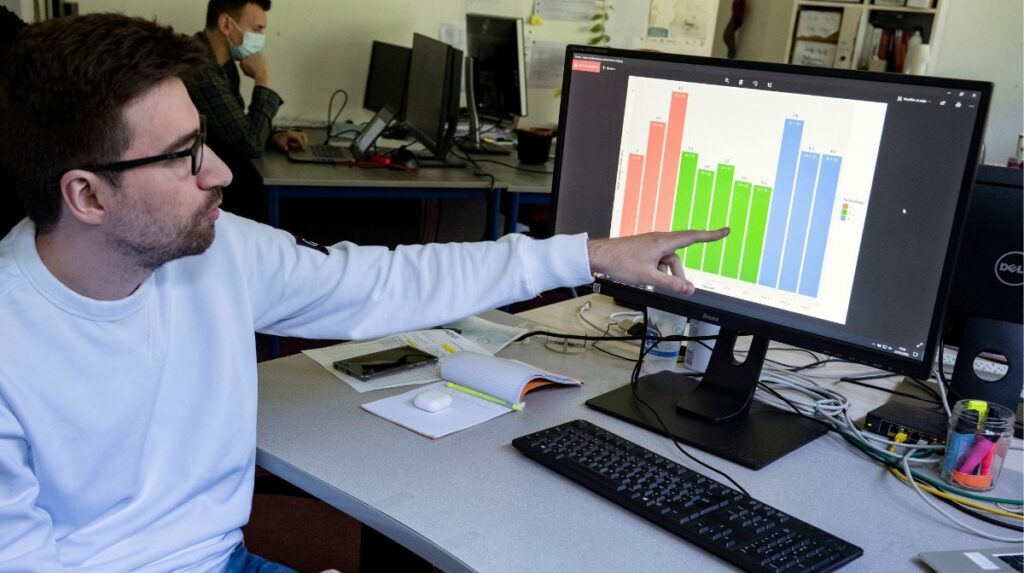 Un homme pointe du doigt un graphique affiché sur son écran d’ordinateur