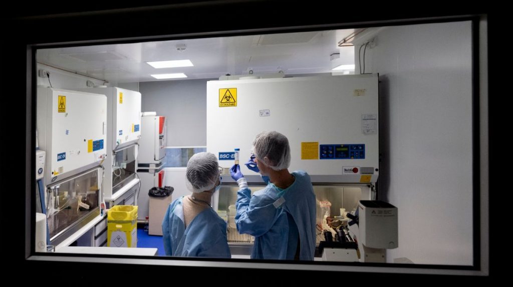 Deux scientifiques pris en photo à travers la vitre d’un laboratoire sécurisé