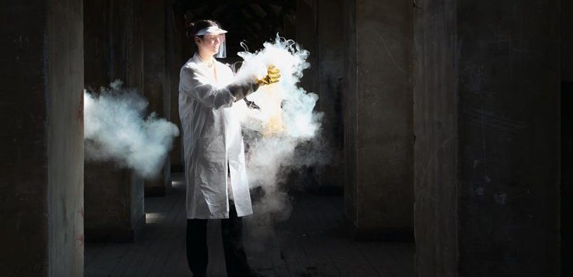Une chercheuse tient un objet qui dégage une importante fumée autour de lui.